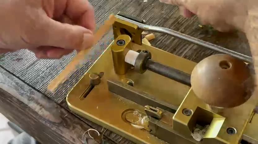 Maker inspecting a gouged oboe cane profile beside the gouger